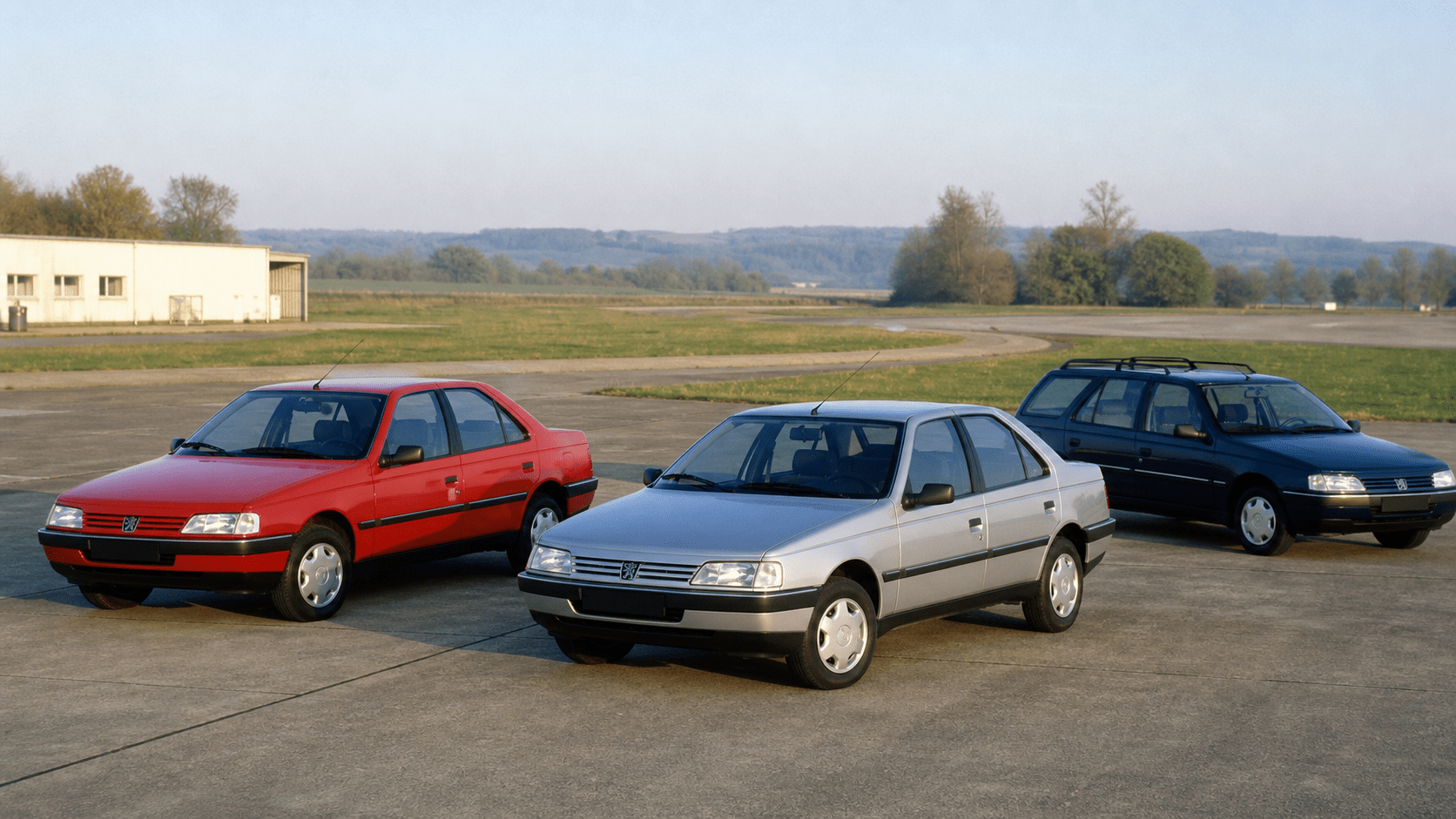 Red and silver Peugeot 405 saloons with a blue Peugeot 405 estate